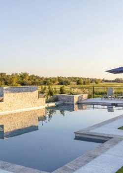 Enjoy the serene luxury pool at Element Ranch Retreats, a perfect blend of relaxation and nature in the heart of Texas. The luxury pool at Element Ranch Retreats, surrounded by elegant lounge chairs and lush landscaping, ideal for relaxation and gatherings.